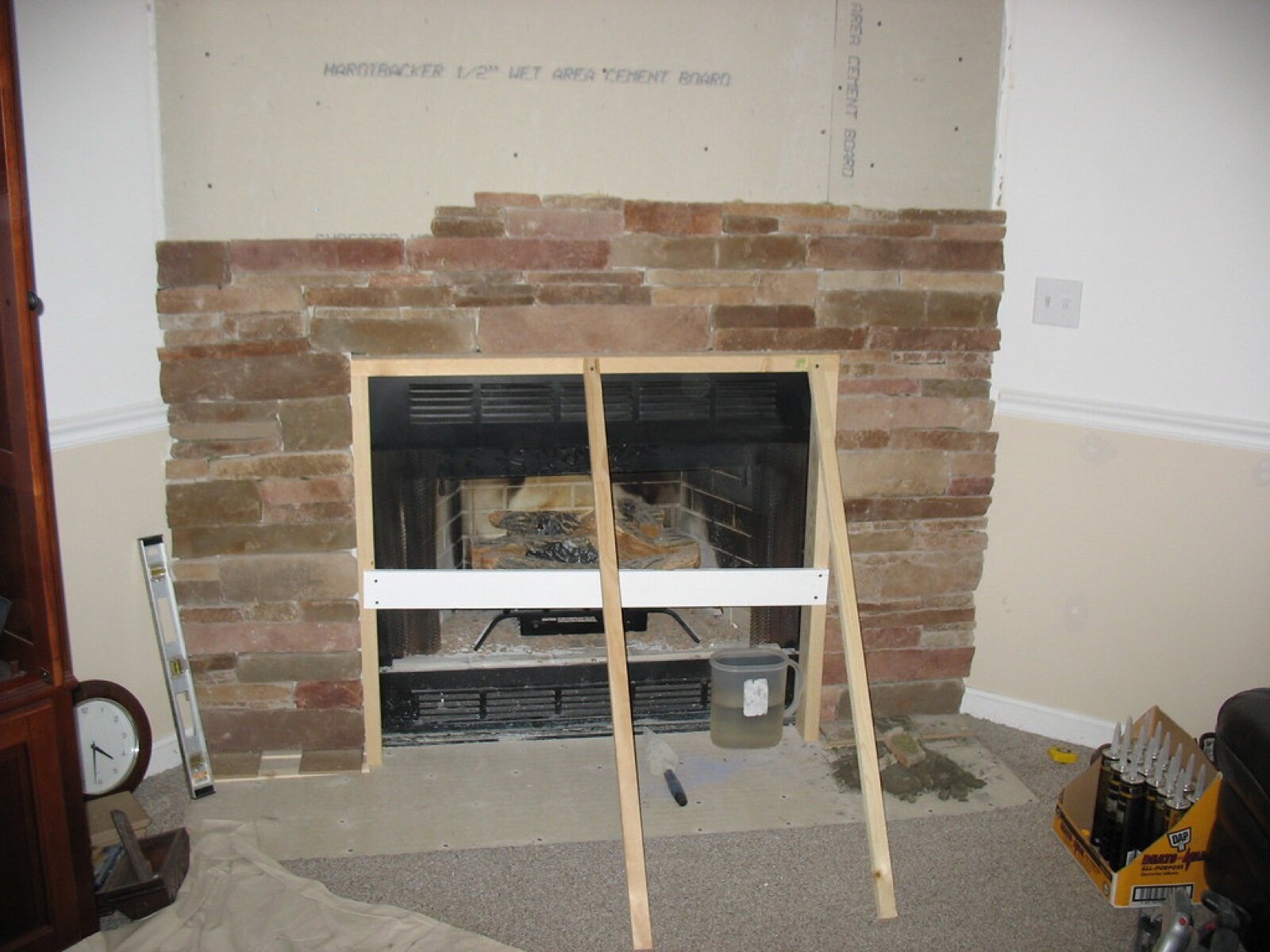 Stacked stone being fitted around a fireplace opening on cement backer board