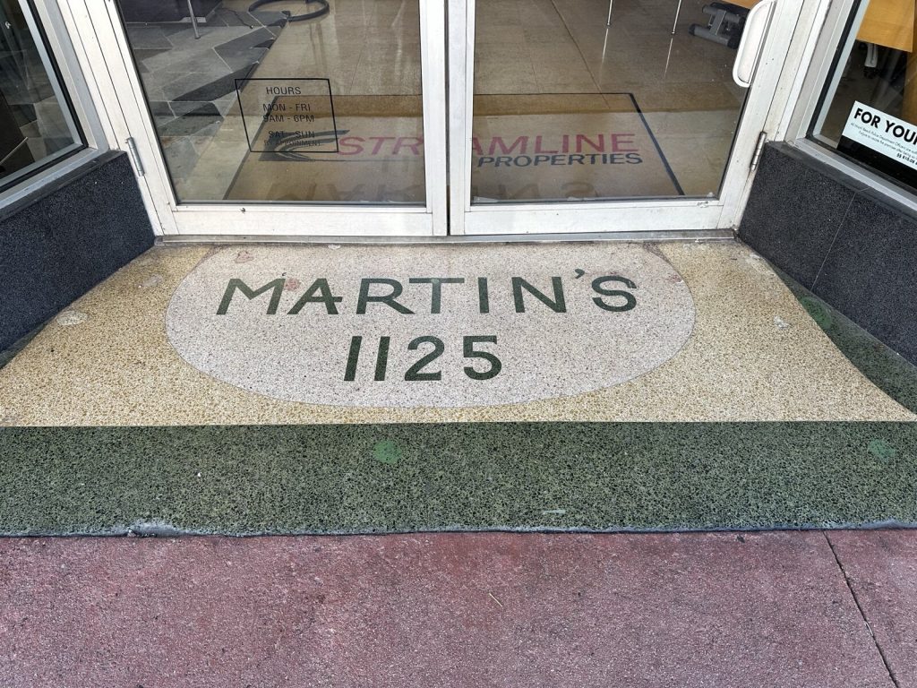 Cement terrazzo doorway floor with green, cream and grey aggregate chips and inlaid lettering