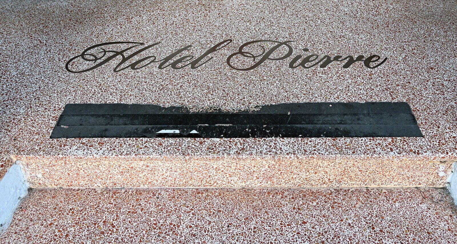 Close-up of a terrazzo step edge showing red and white marble chips through the full depth