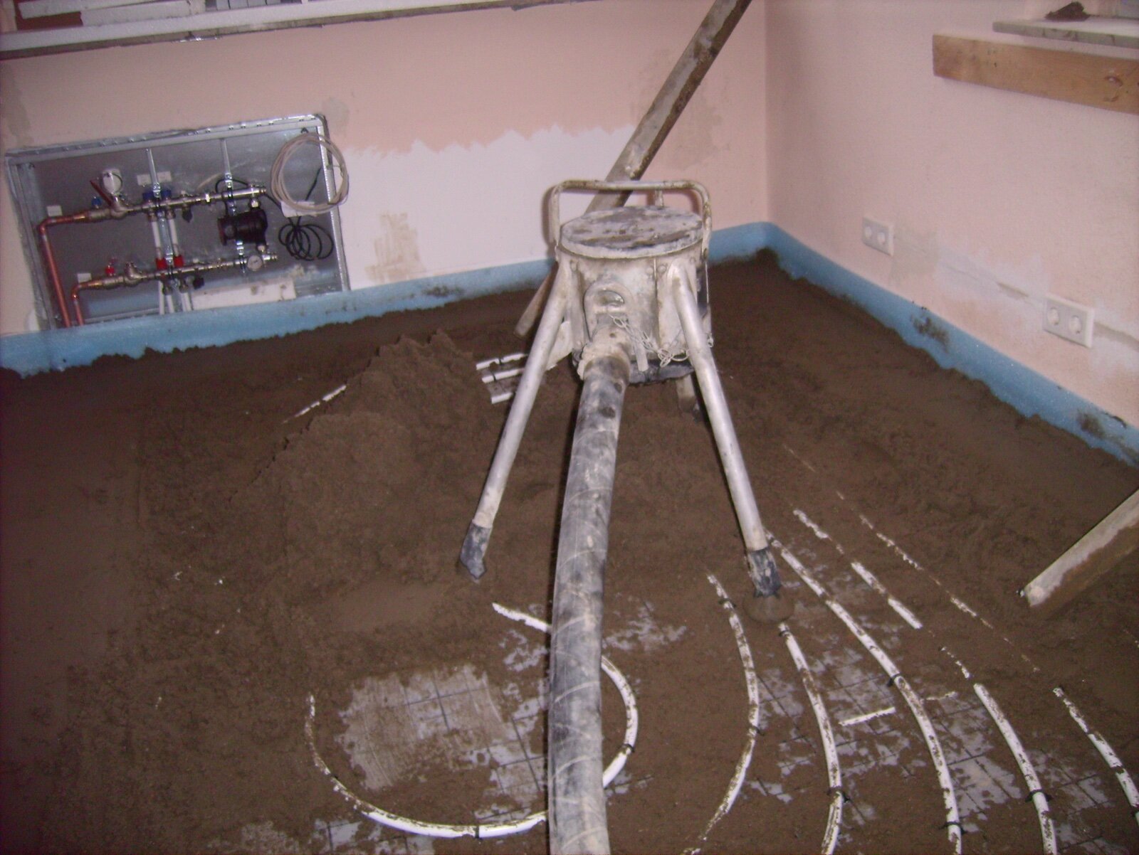 Sand and cement screed being laid over underfloor heating pipes